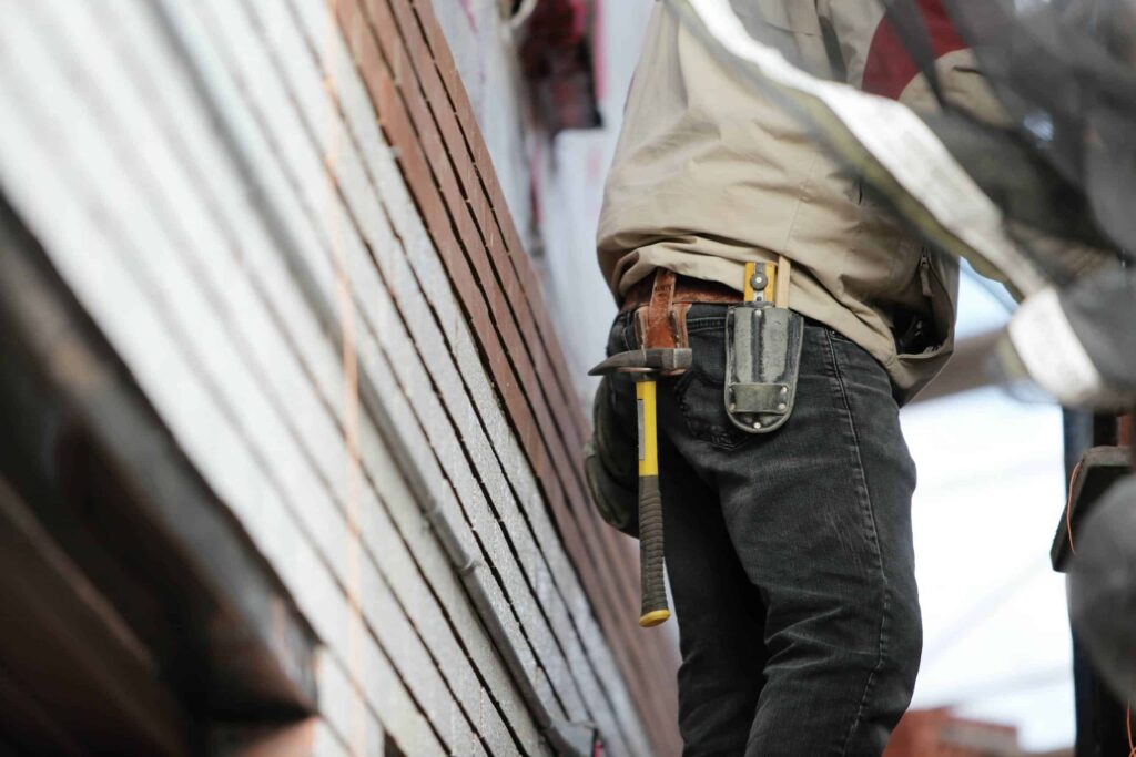 Handyman doing home repairs wearing jeans with hammer on toolbelt